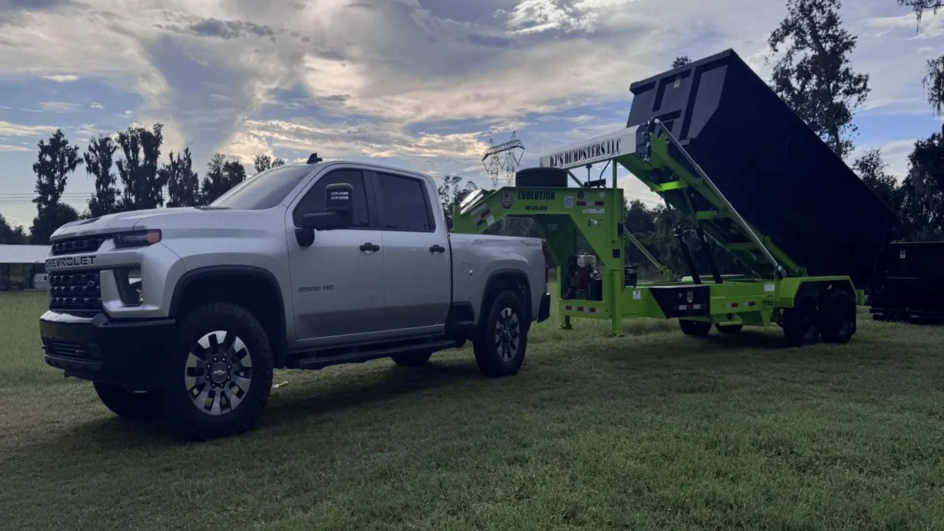DJ's Dumpsters truck and lime-green roll-off trailer lifting a black container in Central Florida