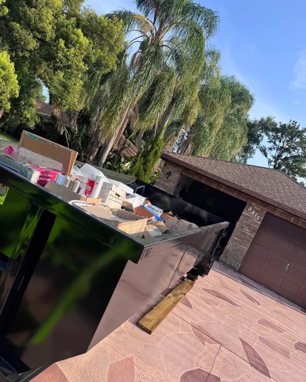 Black roll-off dumpster loaded with household boxes during a residential cleanup